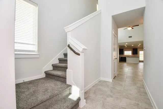 an empty room with fan and kitchen view