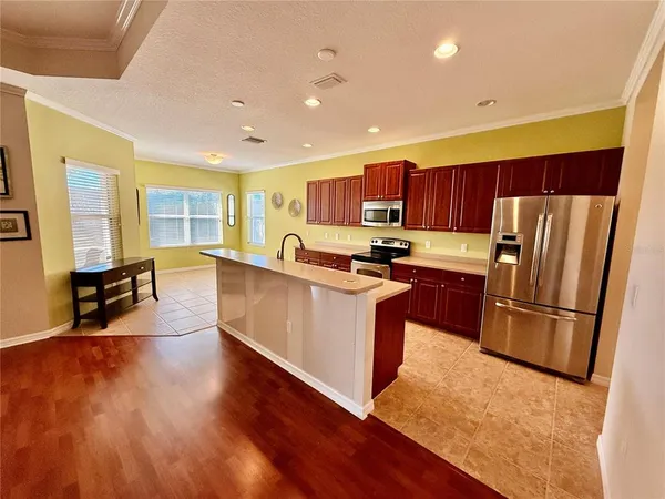 a kitchen with stainless steel appliances wooden floors a refrigerator a stove a sink a dining table and chairs