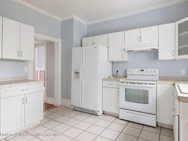 a kitchen with white cabinets and window