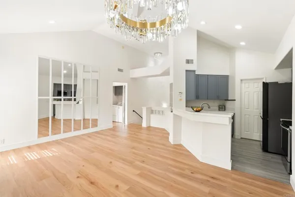 a large white kitchen with wooden floor and a refrigerator