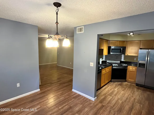 a view of a kitchen with refrigerator stove and wooden floor