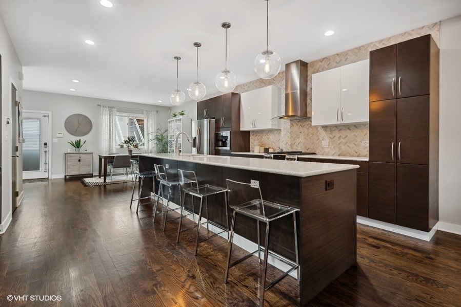 1745 North Troy Street Chicago, IL 60647 - Photo 4 of 29 a kitchen with kitchen island stainless steel appliances a dining table chairs sink and white cabinets