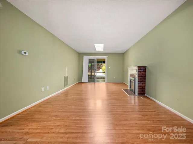a view of empty room with wooden floor and fireplace