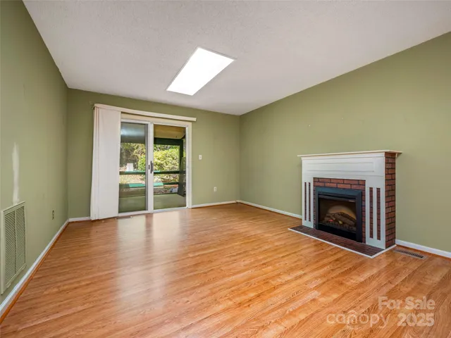 an empty room with wooden floor fireplace and windows