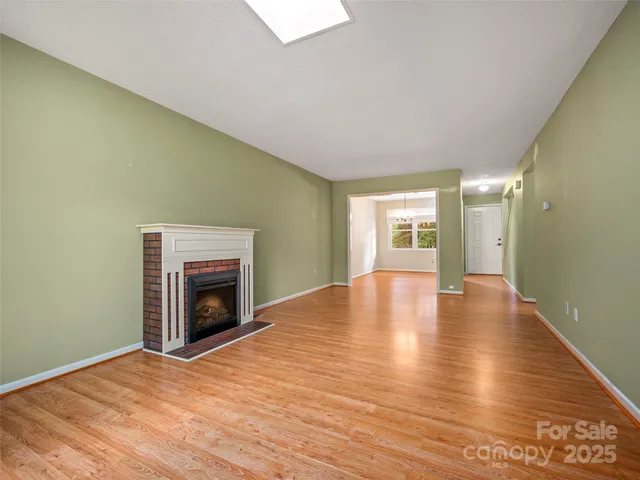 a view of empty room with wooden floor and fireplace