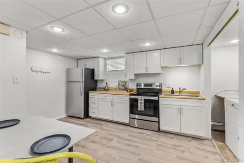 a kitchen with a sink a stove a refrigerator and white cabinets