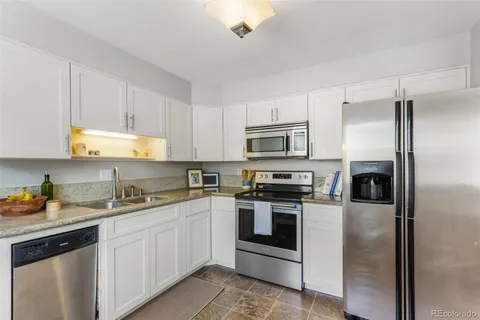 a kitchen with a sink white cabinets and stainless steel appliances