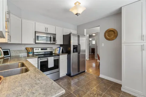 a kitchen with stainless steel appliances granite countertop a refrigerator a stove and a sink