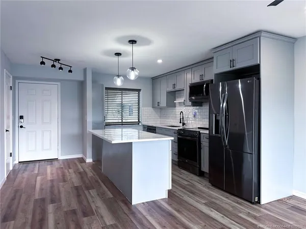 a kitchen with wooden floors and stainless steel appliances
