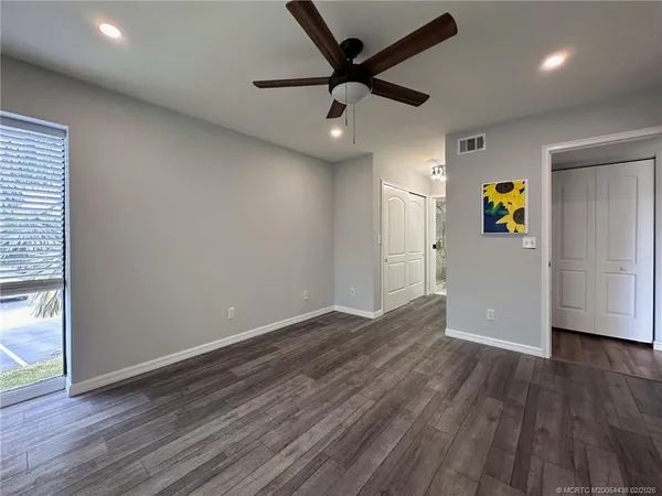 an empty room with wooden floor and a ceiling fan