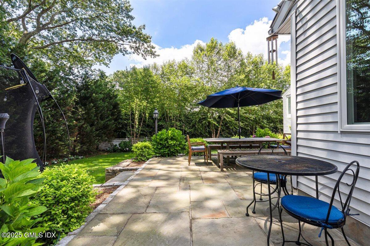 44 Bote Road Greenwich, CT 06830 - Photo 17 of 30 a view of a patio with table and chairs under an umbrella with large trees