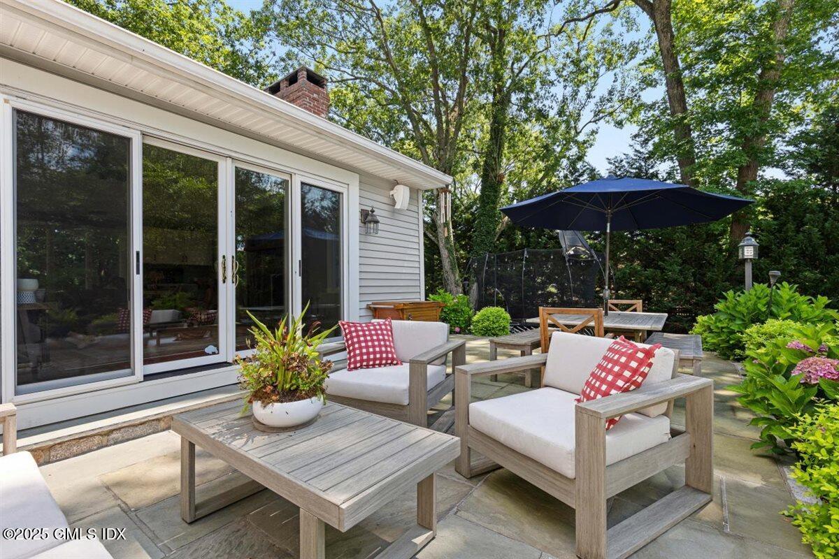 44 Bote Road Greenwich, CT 06830 - Photo 20 of 30 a view of a patio with a table and chairs under an umbrella with a small yard