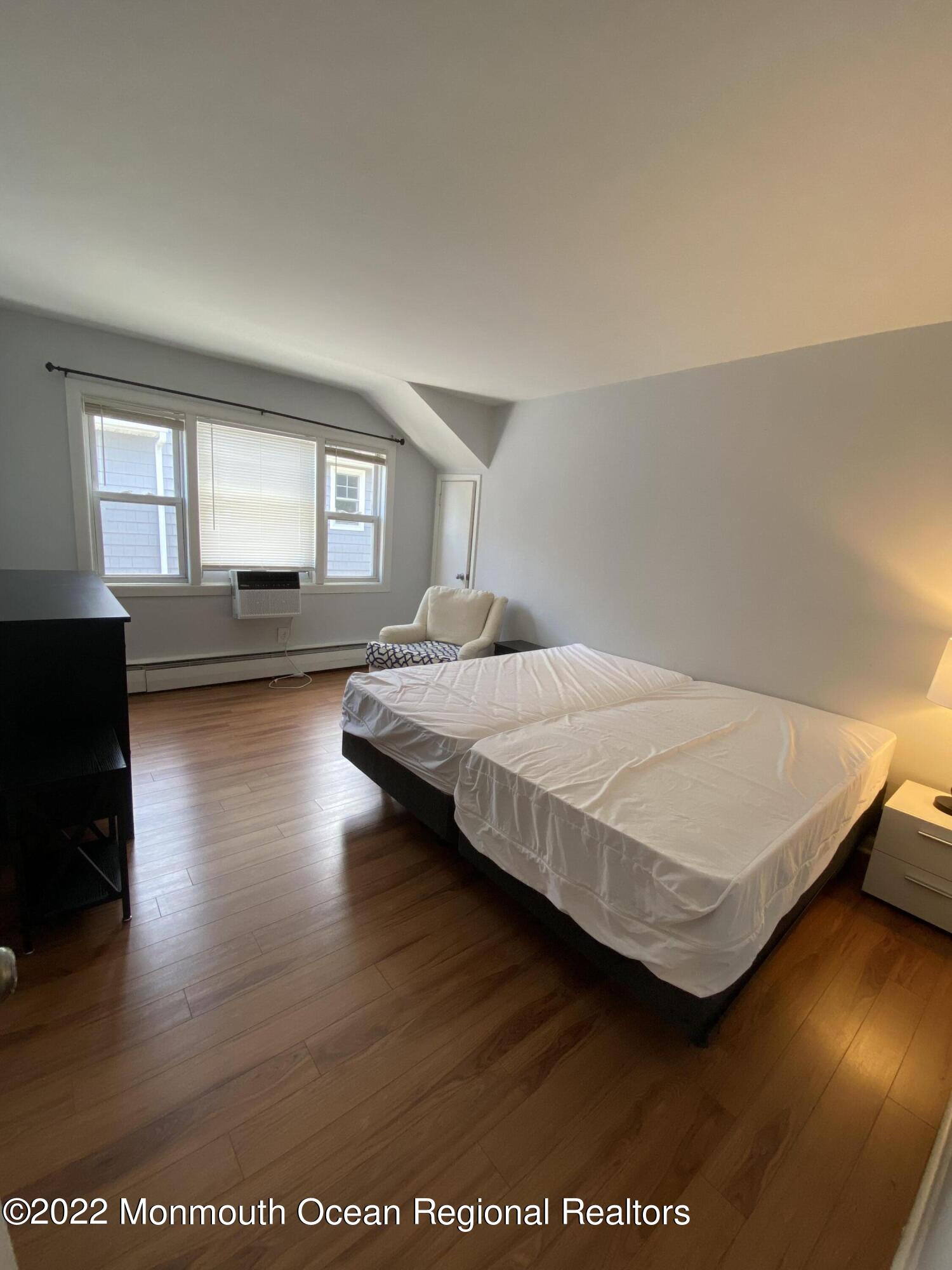 9 Howland Avenue, Unit 2 Long Branch, NJ 07740 - Photo 4 of 8 a bedroom with a bed and wooden floor