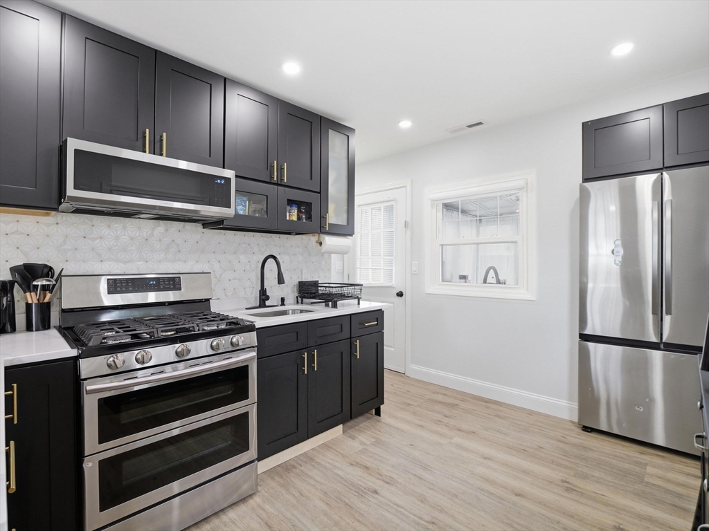 63 Jasper Street Saugus, MA 01906 - Photo 4 of 39 a kitchen with stainless steel appliances granite countertop a stove and a refrigerator