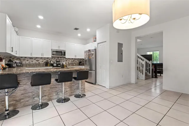 a kitchen with stainless steel appliances kitchen island granite countertop a refrigerator and a stove top oven