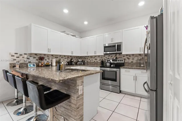 a kitchen with stainless steel appliances granite countertop a stove a sink and a refrigerator