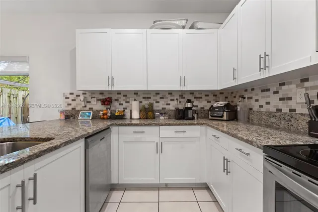 a kitchen with granite countertop white cabinets and white appliances