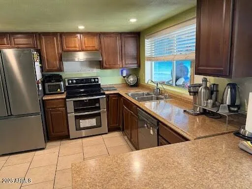 a kitchen with stainless steel appliances a sink a stove a refrigerator cabinets and a counter top space