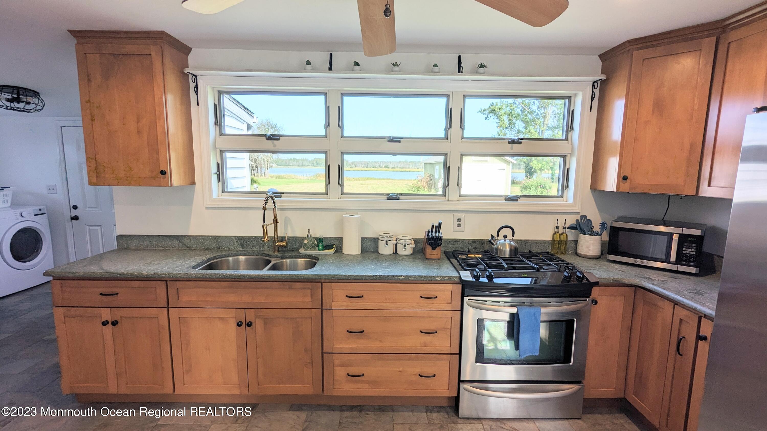303 Baptist Road Newport, NJ 08345 - Photo 9 of 20 a kitchen with stainless steel appliances granite countertop a sink stove cabinets and window