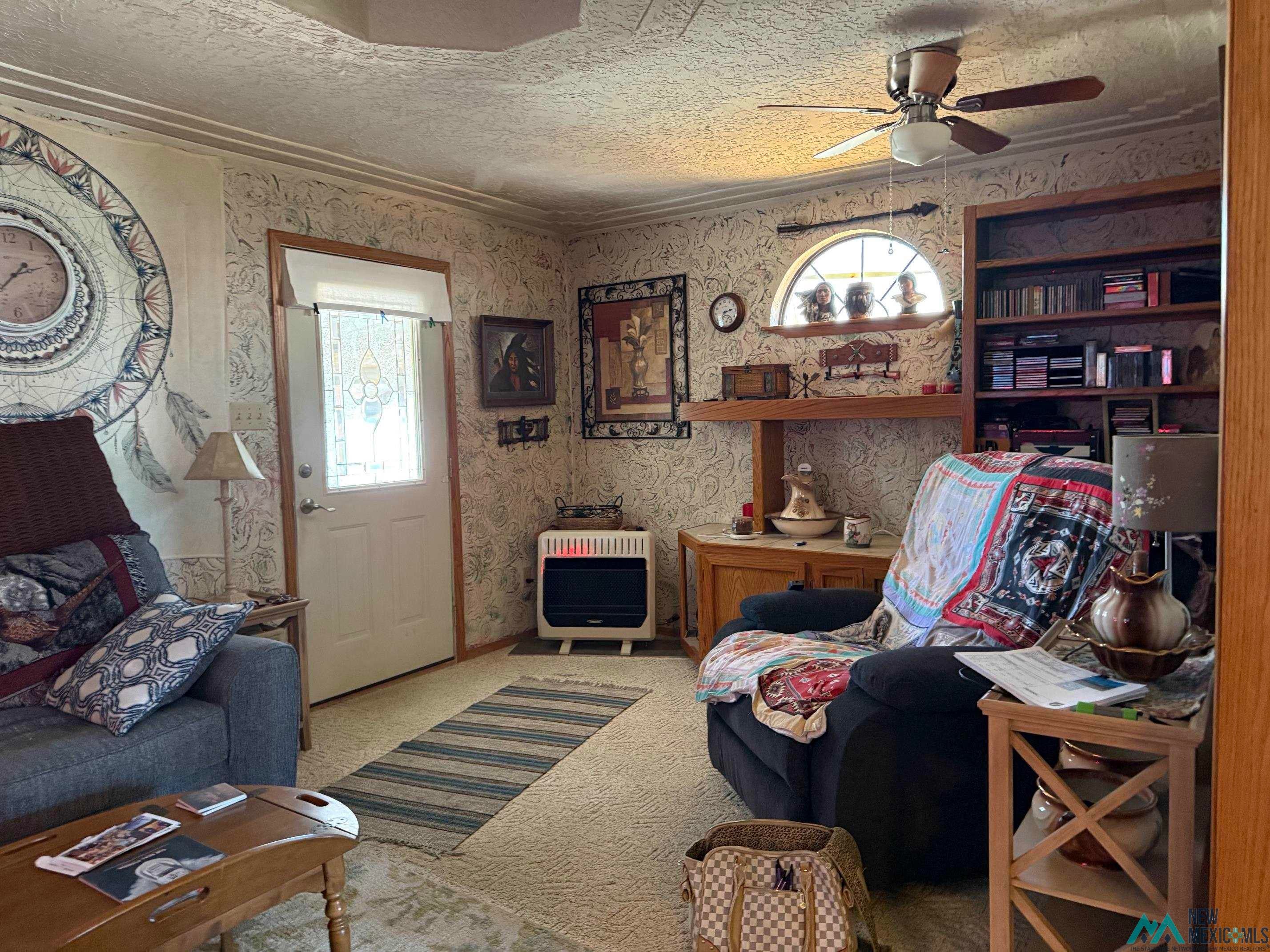 4010 540th Loop Logan, NM 88426 - Photo 3 of 38 Living area with patterned wallpaper, built-in shelving, wood-finish flooring, and a ceiling fan with integrated lighting