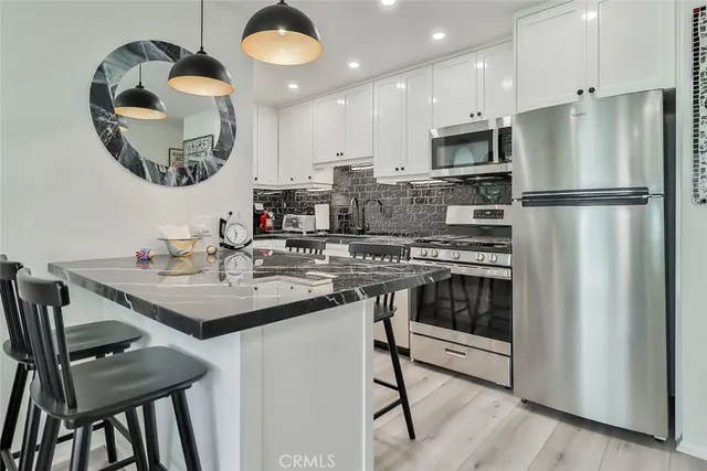 a kitchen with kitchen island granite countertop a sink cabinets a refrigerator and a stove