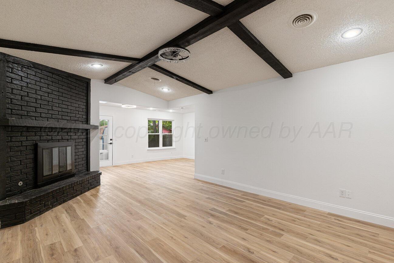 2607 15th Avenue Canyon, TX 79015 - Photo 16 of 54 an empty room with wooden floor a fireplace and windows