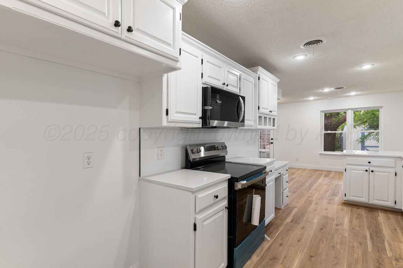 2607 15th Avenue Canyon, TX 79015 - Photo 20 of 54 a kitchen with a sink a stove top oven and white kitchen island