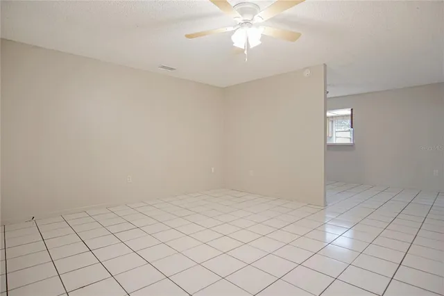 an empty room with windows and fan