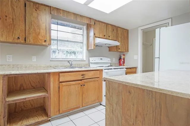 a kitchen with granite countertop a sink window and cabinets