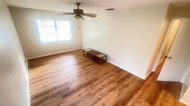a view of empty room with wooden floor and fan