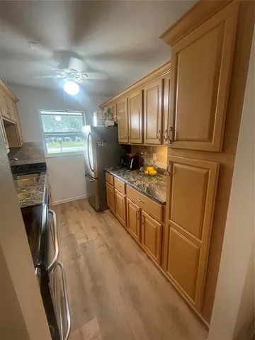a kitchen with granite countertop a refrigerator a sink a stove and cabinets