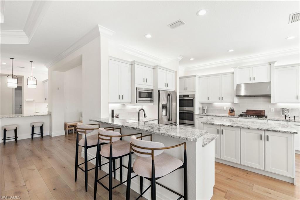 4308 Caldera Circle Naples, FL 34119 - Photo 12 of 44 a kitchen with stainless steel appliances kitchen island granite countertop a stove a sink a dining table and chairs