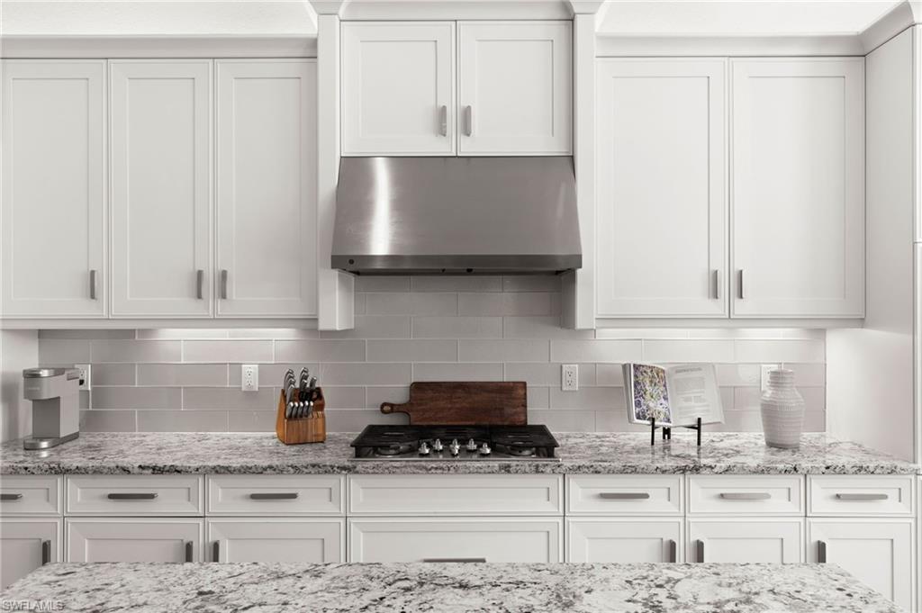4308 Caldera Circle Naples, FL 34119 - Photo 14 of 44 a kitchen with granite countertop a stove a sink and a white cabinets