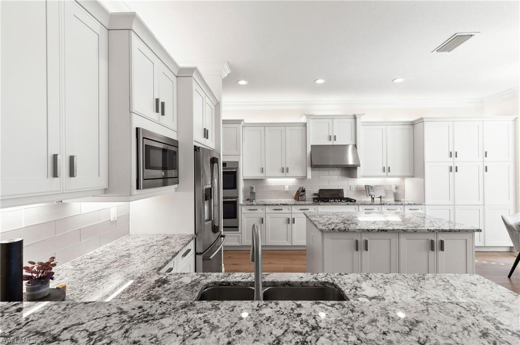 4308 Caldera Circle Naples, FL 34119 - Photo 15 of 44 a kitchen with stainless steel appliances kitchen island granite countertop a sink and cabinets