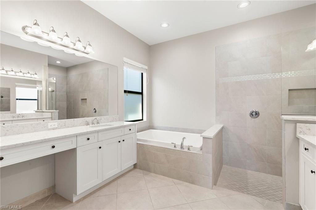 4308 Caldera Circle Naples, FL 34119 - Photo 21 of 44 a bathroom with a granite countertop sink a large mirror and a bathtub