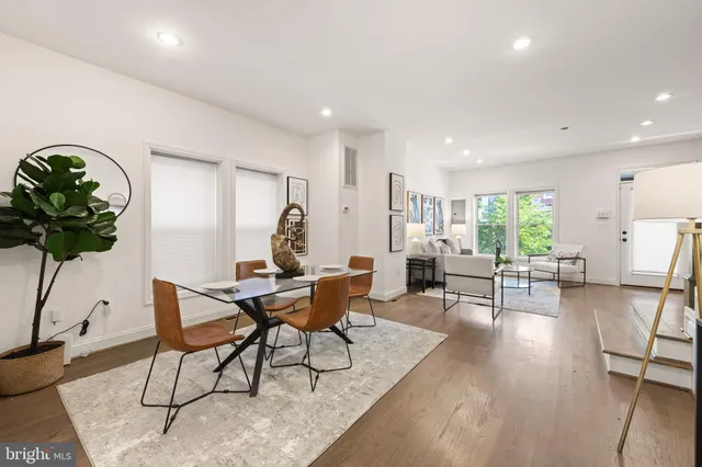 a kitchen with stainless steel appliances granite countertop a refrigerator a stove a sink a microwave a dining table and chairs with wooden floor