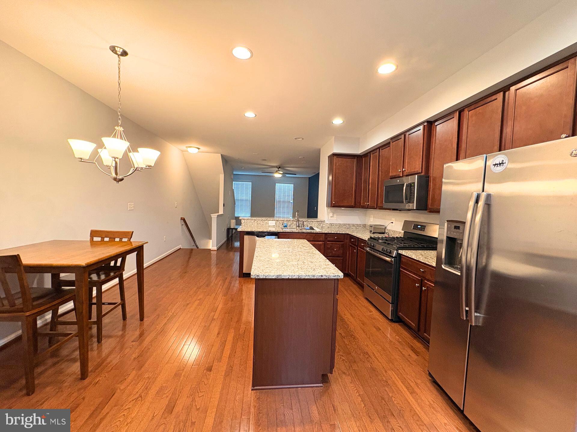 1718 Featherstone Road Woodbridge, VA 22191 - Photo 11 of 23 a kitchen with stainless steel appliances kitchen island granite countertop wooden floors a stove and a refrigerator