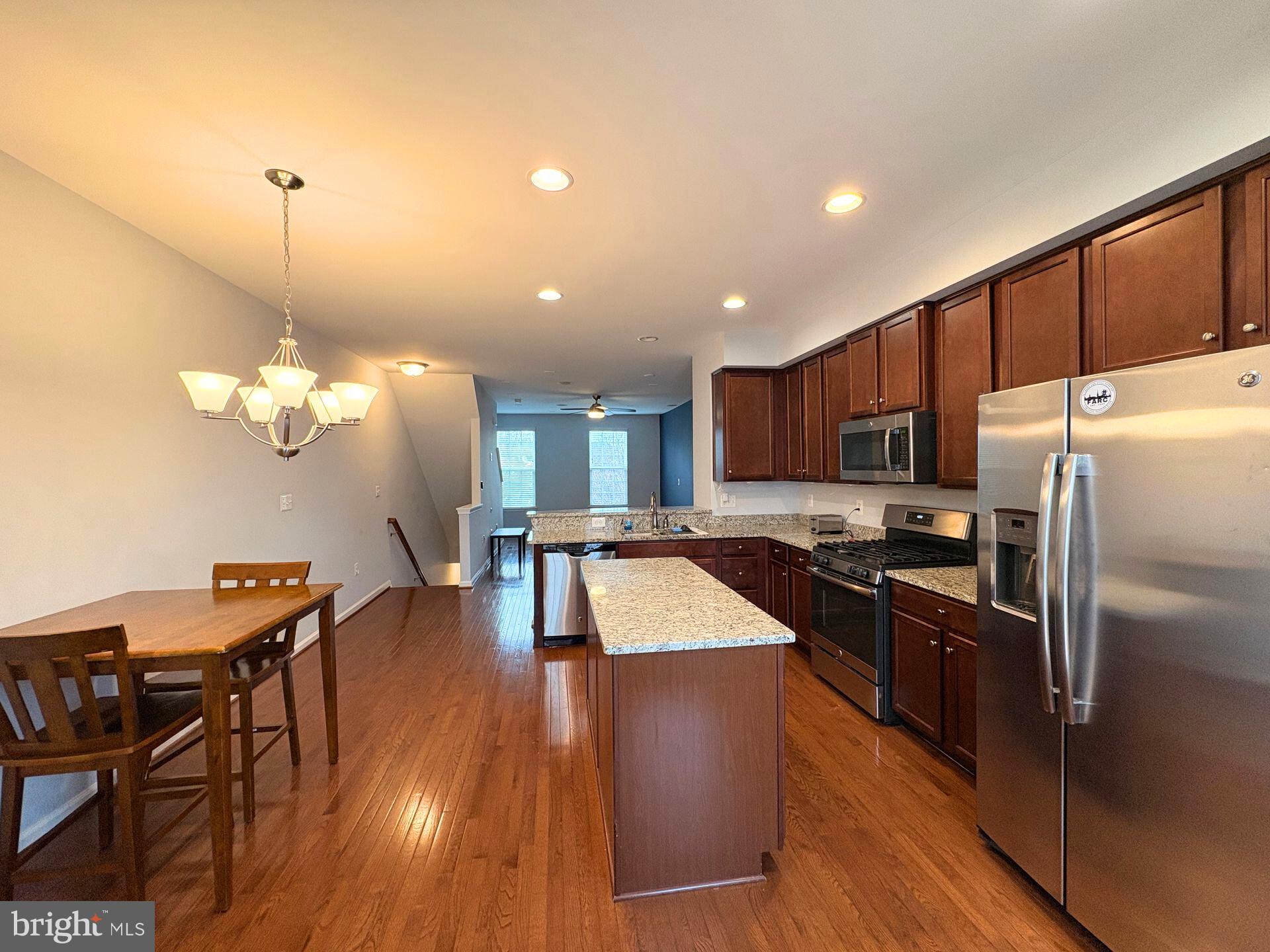 1718 Featherstone Road Woodbridge, VA 22191 - Photo 13 of 23 a kitchen with stainless steel appliances granite countertop a stove refrigerator a dining table and chairs with wooden floor