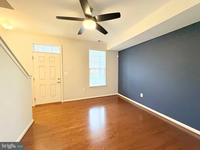 an empty room with wooden floor fan and windows