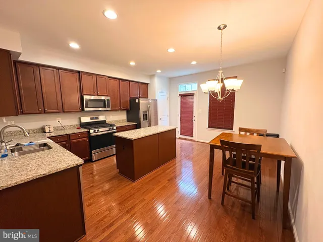 a kitchen with a refrigerator a stove top oven a sink dishwasher and wooden floor