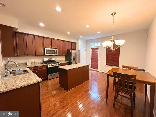 a kitchen with kitchen island granite countertop wooden floors wooden cabinets a center island and stainless steel appliances