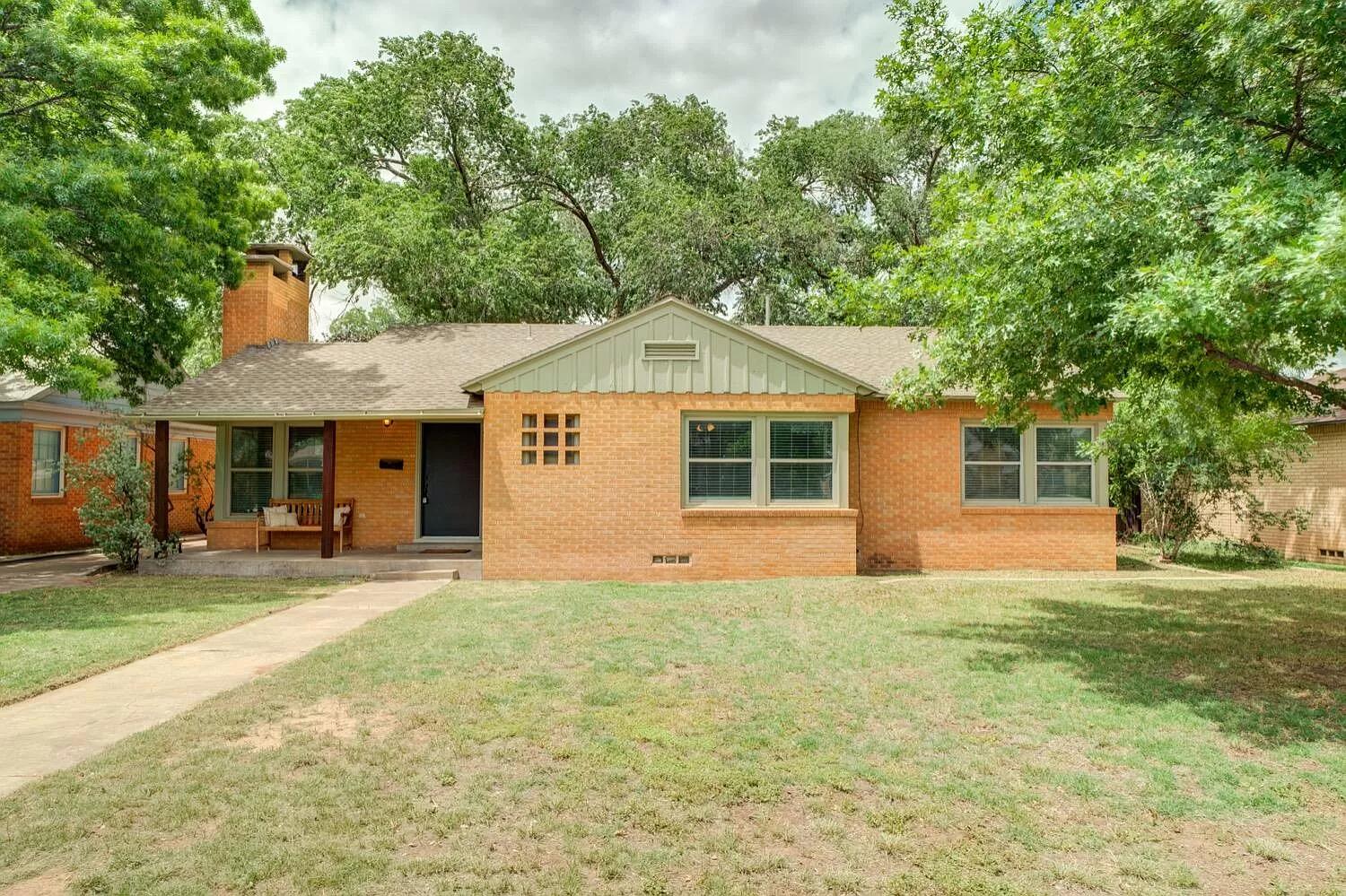 a front view of a house with a yard and trees