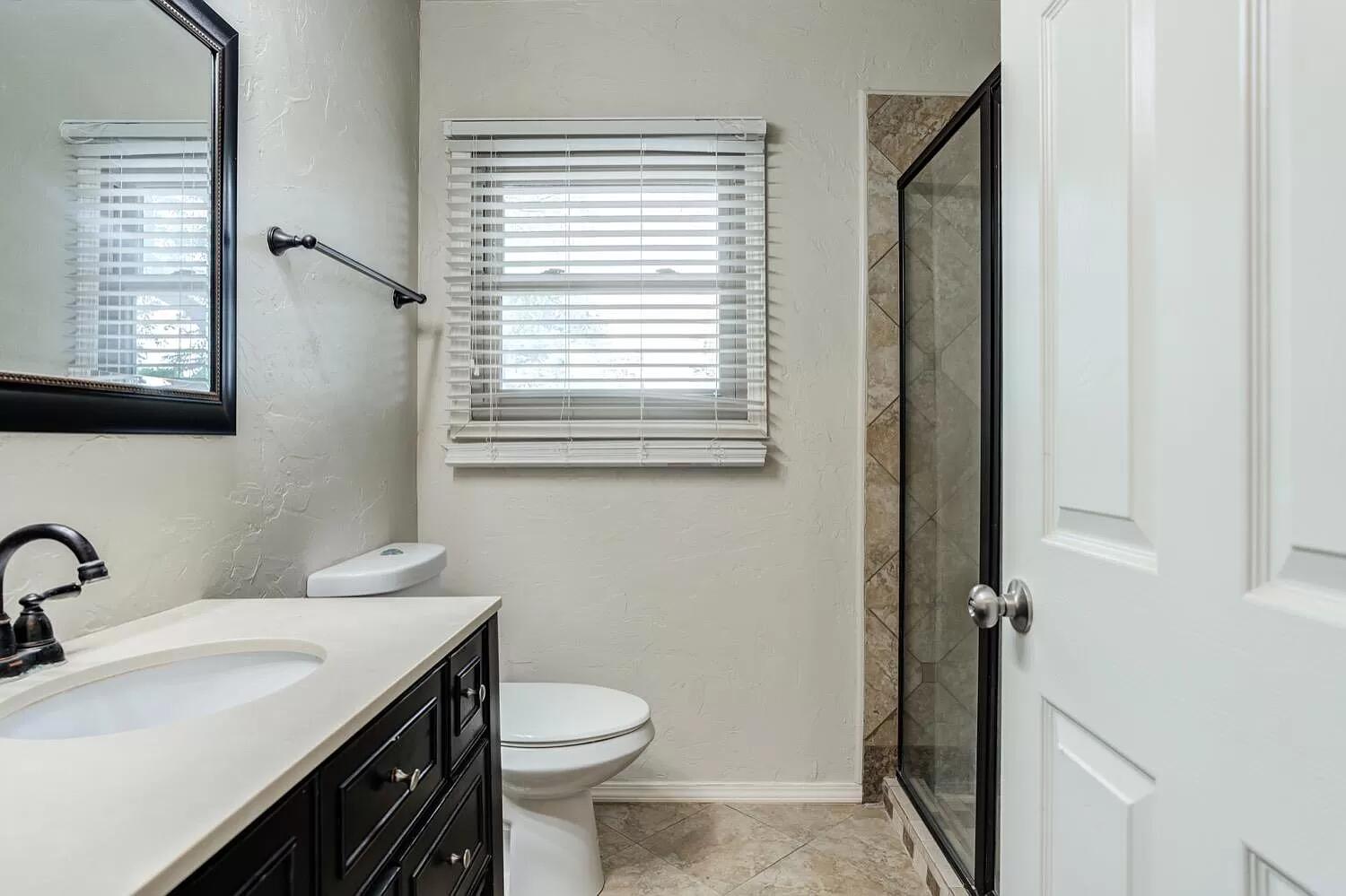 3204 28th Street Lubbock, TX 79410 - Photo 13 of 24 a bathroom with a sink a toilet and a window