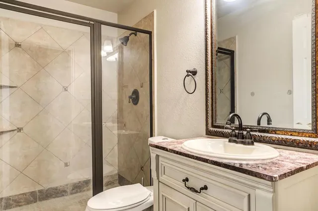 a bathroom with a granite countertop sink toilet and shower