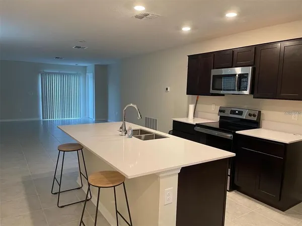 a kitchen with stainless steel appliances kitchen island granite countertop a sink a microwave and a refrigerator