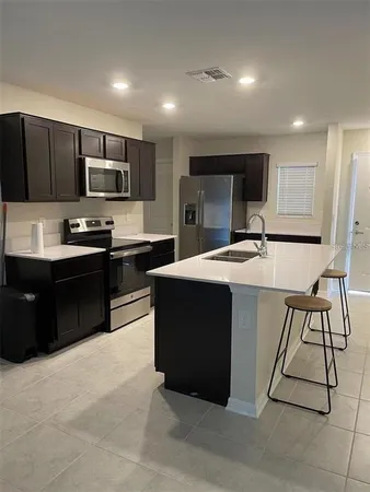 a kitchen with stainless steel appliances kitchen island granite countertop a sink dishwasher stove top oven and wooden cabinets