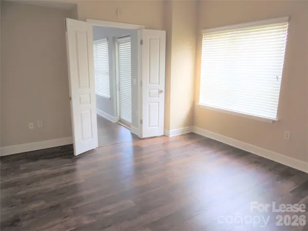 an empty room with wooden floor and windows