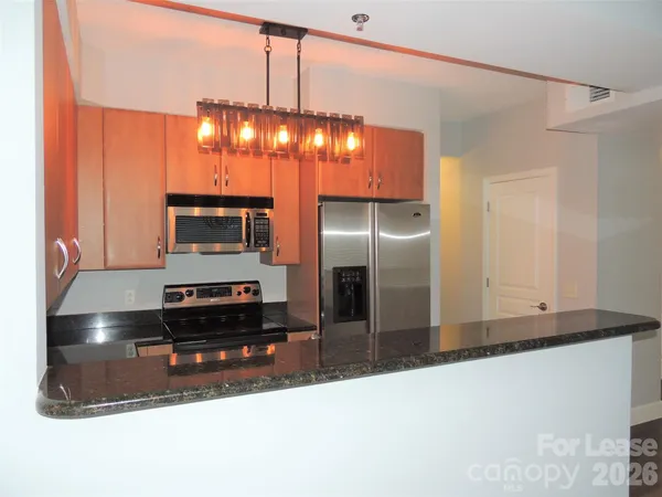 a kitchen with stainless steel appliances granite countertop a refrigerator a stove and a sink with granite countertops