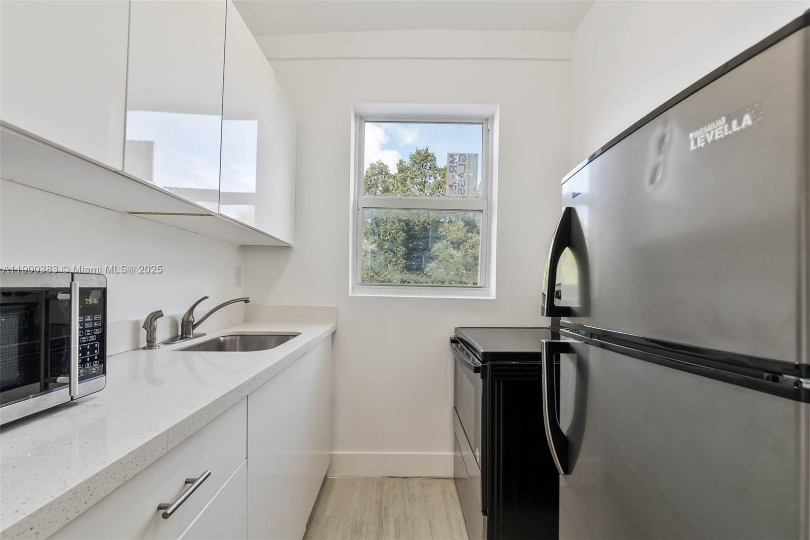 1051 Northwest 2nd Street, Unit 12 Miami, FL 33128 - Photo 5 of 14 a kitchen with a sink a window and stainless steel appliances