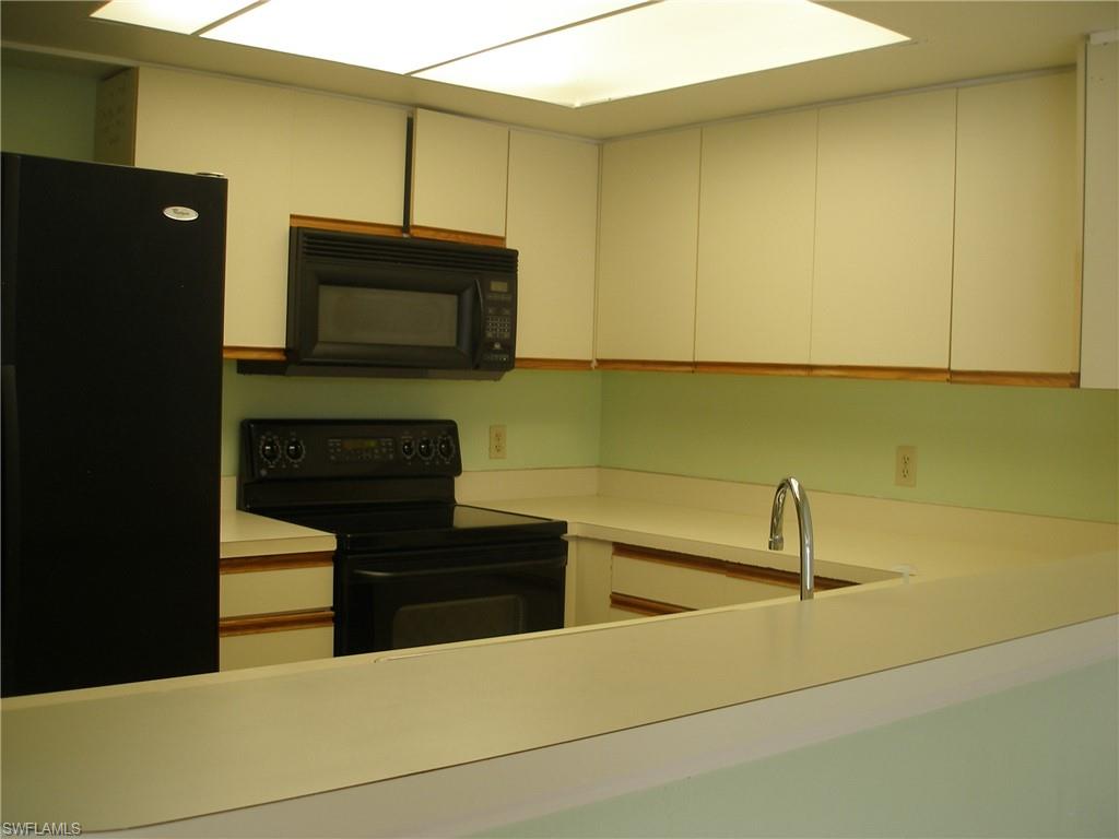3342 Timberwood Circle Naples, FL 34105 - Photo 5 of 17 a kitchen with stainless steel appliances kitchen island a sink dishwasher a stove and a microwave oven